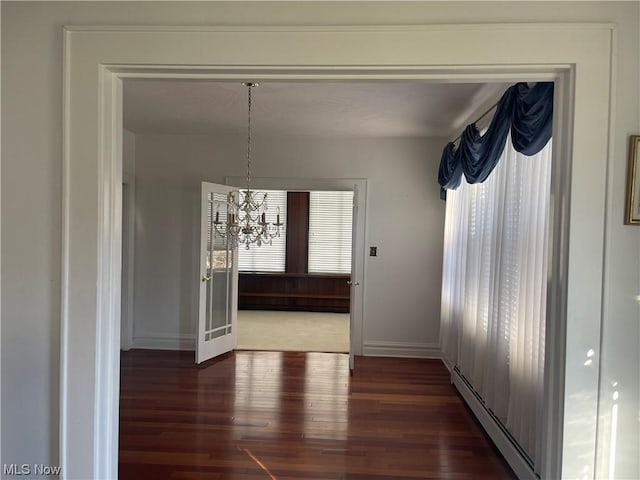 unfurnished dining area featuring a chandelier, dark hardwood / wood-style flooring, and baseboard heating