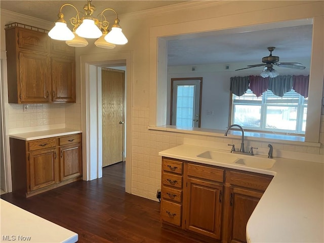 kitchen featuring dark hardwood / wood-style flooring, ceiling fan with notable chandelier, crown molding, sink, and decorative light fixtures