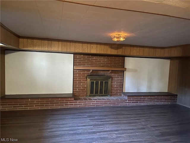 unfurnished living room featuring wood walls, a fireplace, and dark hardwood / wood-style floors