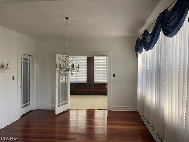 unfurnished dining area featuring a chandelier, dark hardwood / wood-style floors, and a wealth of natural light