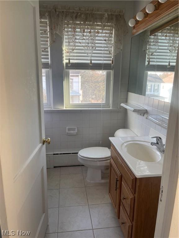 bathroom featuring vanity, a baseboard radiator, tile walls, tile patterned flooring, and toilet