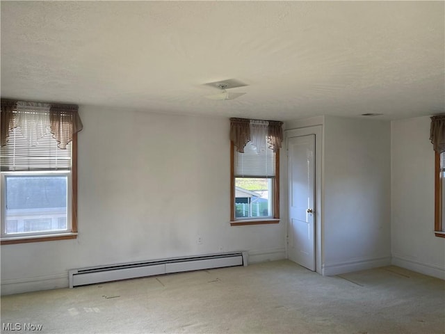 carpeted spare room with a baseboard heating unit