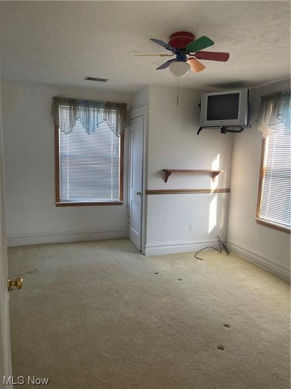 empty room with ceiling fan and light carpet