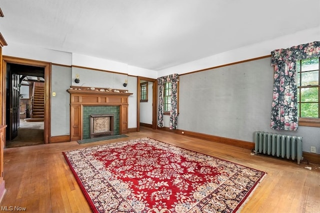 living room featuring hardwood / wood-style floors, a tiled fireplace, and radiator heating unit