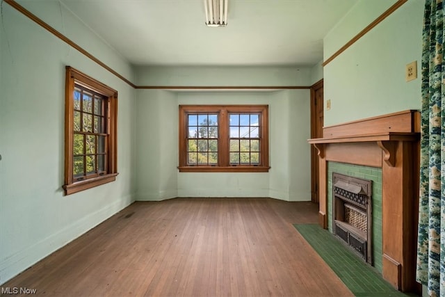 unfurnished living room with wood-type flooring and a tile fireplace