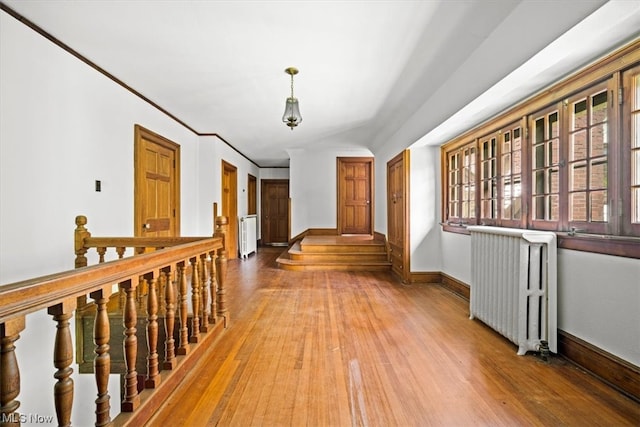 hallway with hardwood / wood-style flooring, crown molding, and radiator heating unit