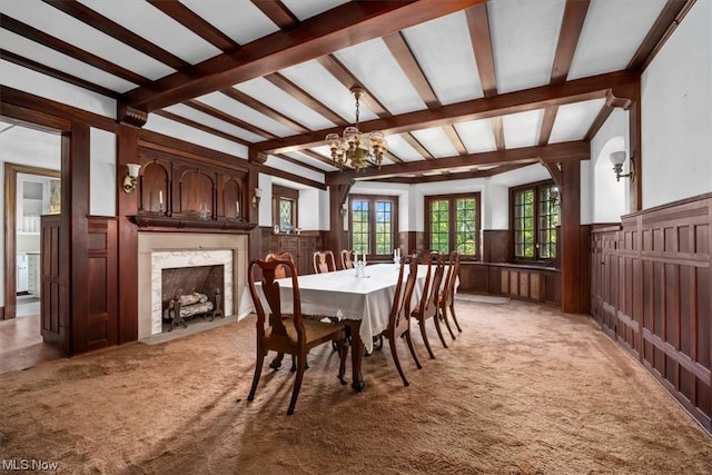 carpeted dining room with an inviting chandelier, beam ceiling, and a fireplace