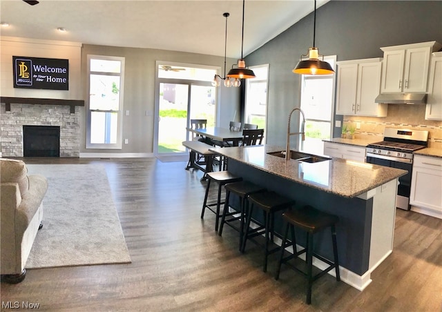 kitchen featuring a fireplace, vaulted ceiling, gas stove, and a healthy amount of sunlight