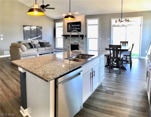 kitchen with dark wood-style floors, a stone fireplace, stainless steel dishwasher, and a sink