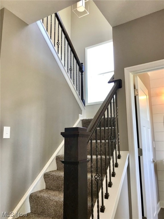 staircase featuring a towering ceiling and baseboards