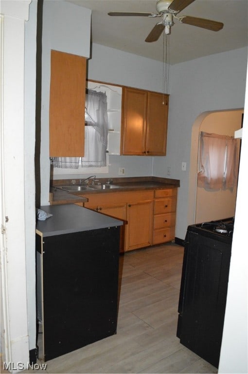 kitchen with ceiling fan, black range oven, light hardwood / wood-style flooring, and sink