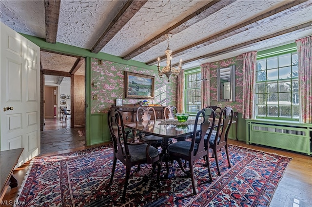 dining space with radiator, beamed ceiling, hardwood / wood-style flooring, and plenty of natural light