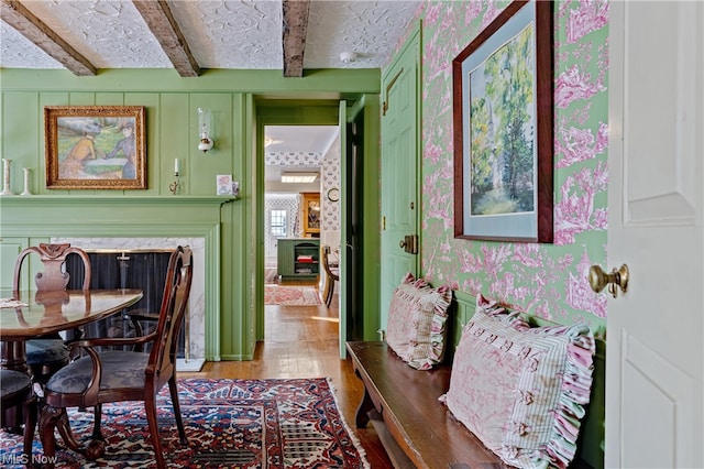 dining room with a high end fireplace, light wood-type flooring, and beam ceiling