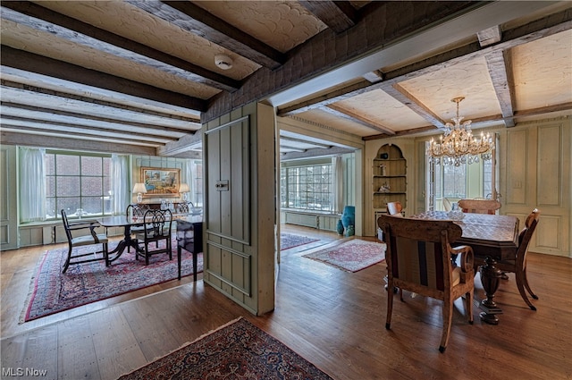 dining area featuring a notable chandelier, wood-type flooring, and beam ceiling