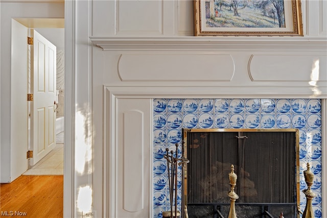 details featuring a tiled fireplace and hardwood / wood-style flooring