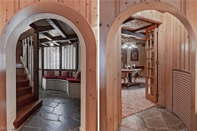 hall featuring beamed ceiling and wooden walls