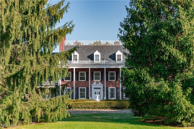 view of front of house featuring a front lawn and a balcony