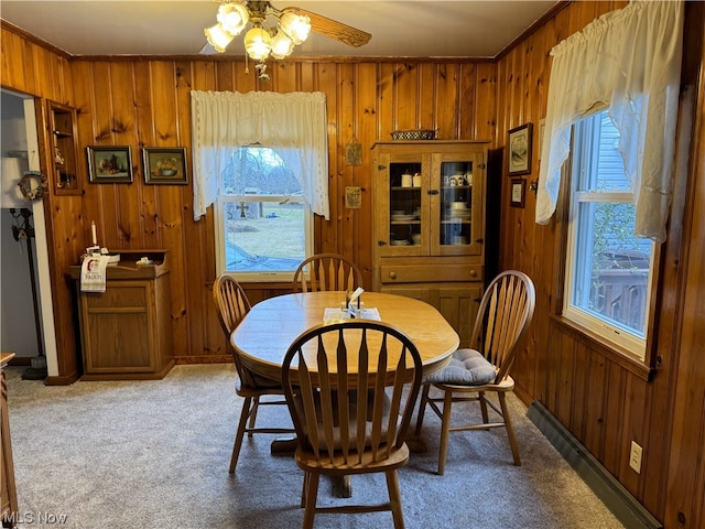 dining area featuring carpet flooring, ceiling fan, crown molding, and wooden walls