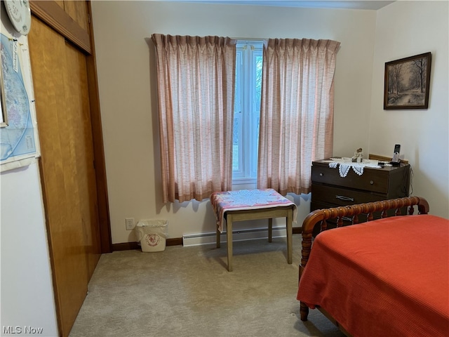 carpeted bedroom featuring white fridge, a closet, and a baseboard heating unit