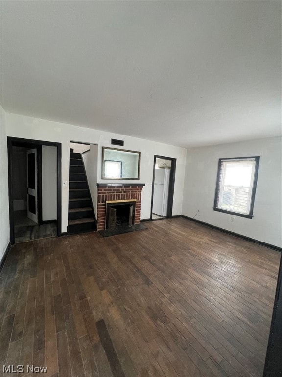 unfurnished living room featuring dark wood-type flooring and a fireplace