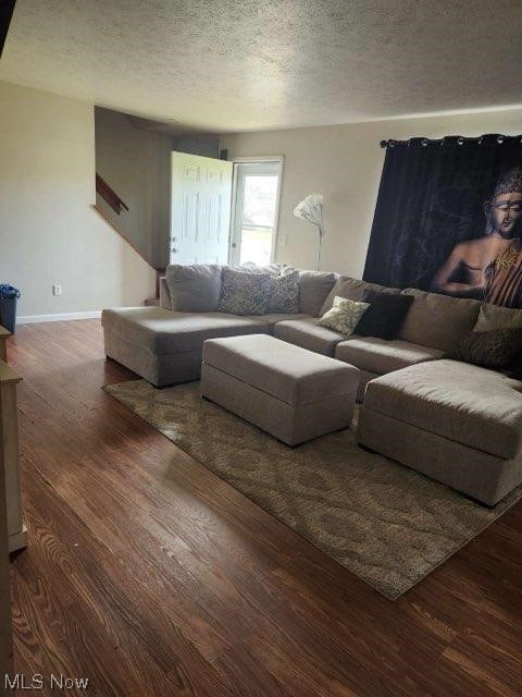 living room with a textured ceiling and dark wood-type flooring