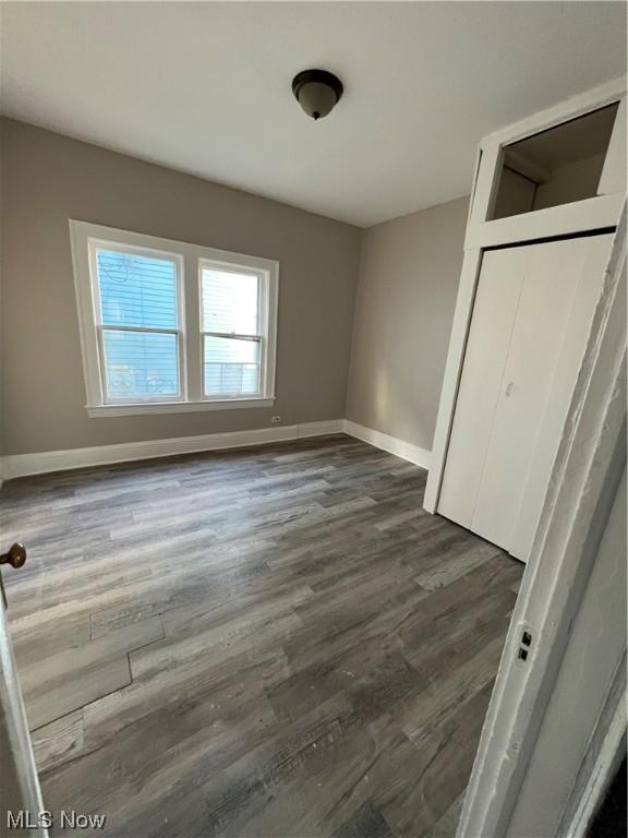 unfurnished bedroom with dark hardwood / wood-style flooring and a closet