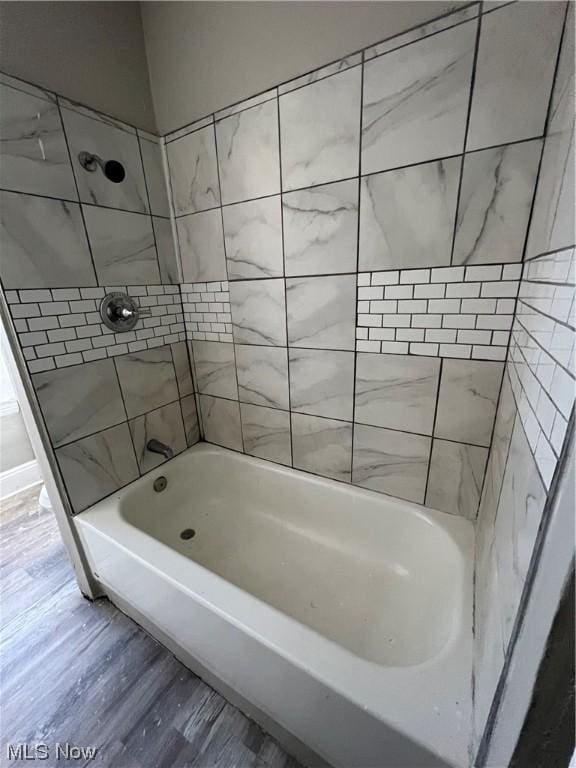 bathroom with hardwood / wood-style floors and tiled shower / bath