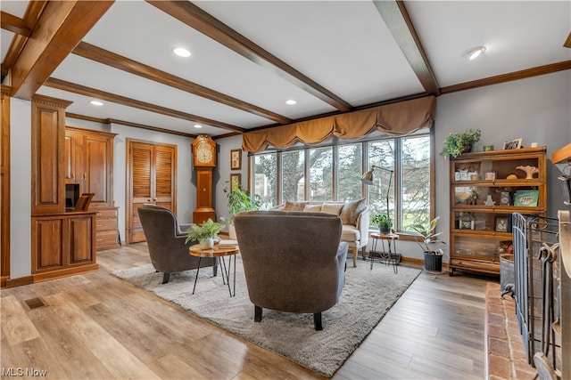 living room with beamed ceiling, light hardwood / wood-style flooring, and ornamental molding