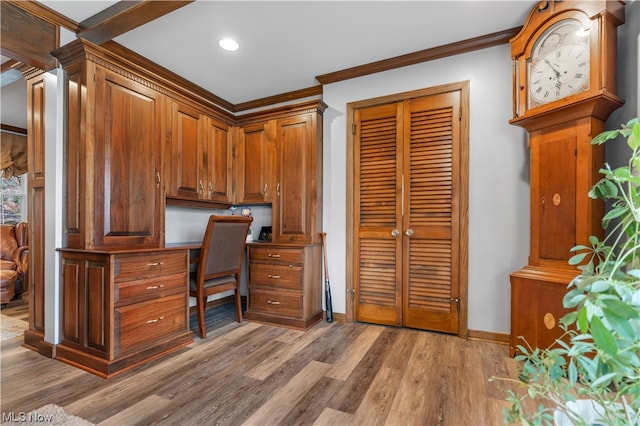 home office with ornamental molding, hardwood / wood-style flooring, and built in desk