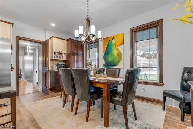 dining room with light hardwood / wood-style floors and a notable chandelier