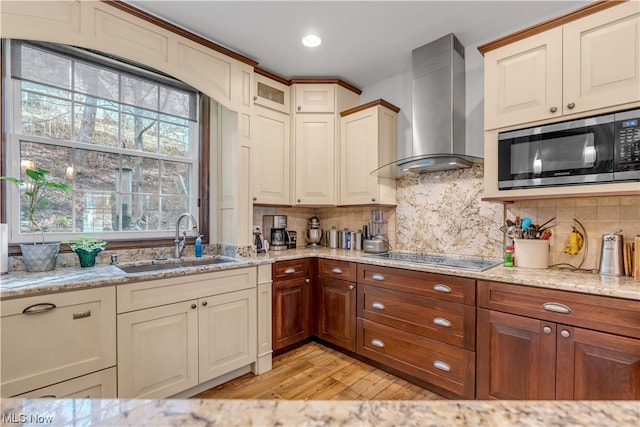 kitchen featuring stainless steel microwave, wall chimney range hood, backsplash, light hardwood / wood-style floors, and sink