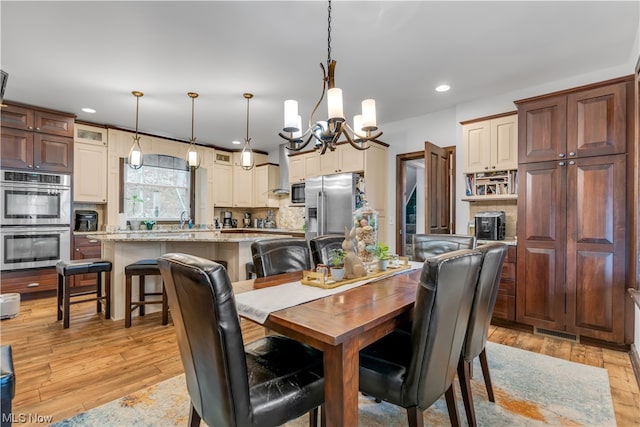 dining area with light wood-type flooring and an inviting chandelier