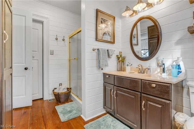 bathroom featuring vanity, a shower with door, hardwood / wood-style flooring, and toilet