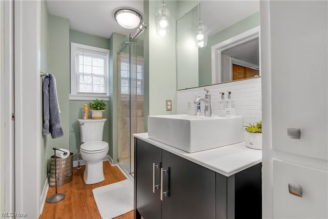 bathroom featuring vanity, decorative backsplash, hardwood / wood-style floors, an enclosed shower, and toilet