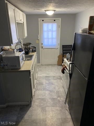 kitchen featuring white range, black refrigerator, and a textured ceiling