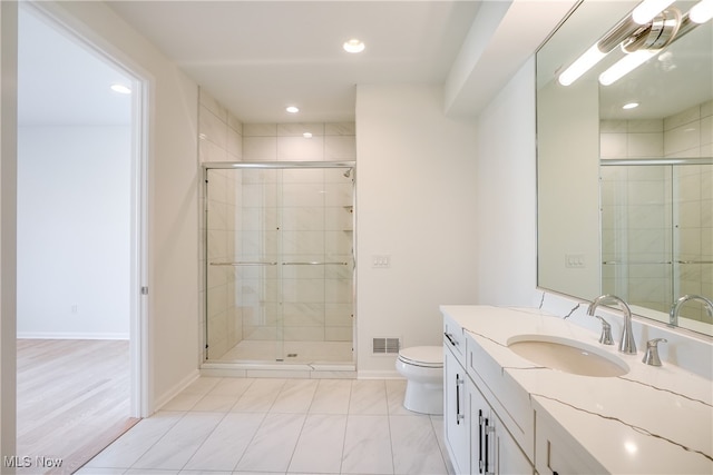 bathroom with hardwood / wood-style flooring, vanity, an enclosed shower, and toilet