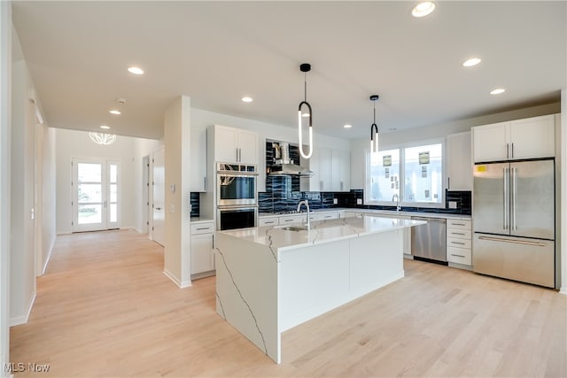 kitchen with a kitchen island with sink, light hardwood / wood-style flooring, white cabinets, and stainless steel appliances