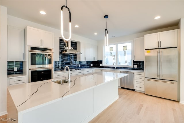 kitchen featuring a kitchen island with sink, sink, hanging light fixtures, and appliances with stainless steel finishes