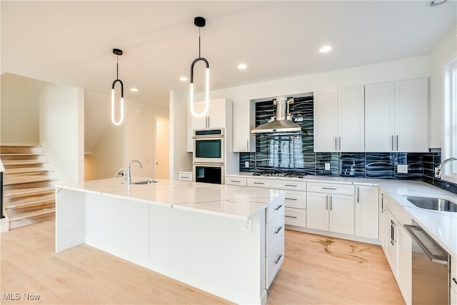 kitchen with white cabinetry, stainless steel appliances, and wall chimney range hood