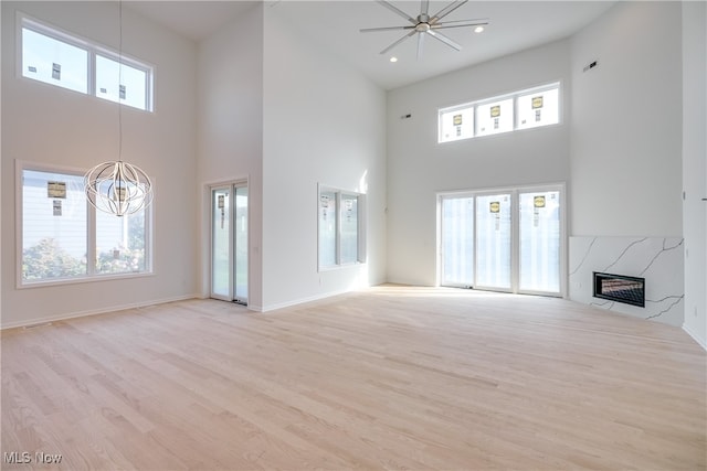 unfurnished living room with a high end fireplace, a high ceiling, light hardwood / wood-style floors, and plenty of natural light