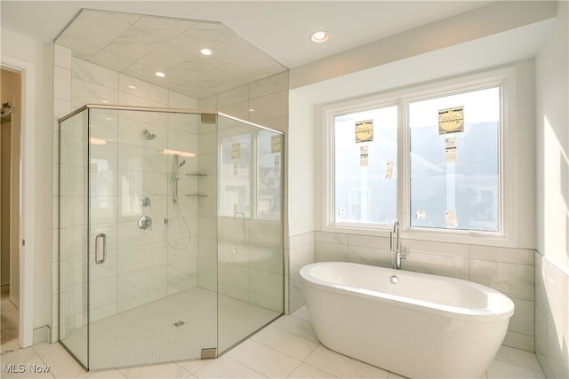 bathroom featuring tile patterned flooring, separate shower and tub, and tile walls