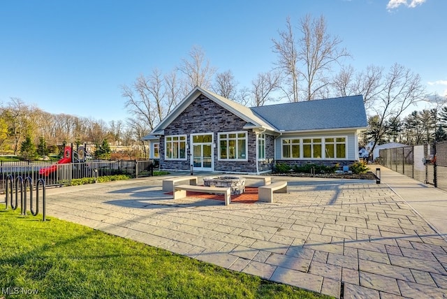 back of property with a playground, a patio, and an outdoor fire pit