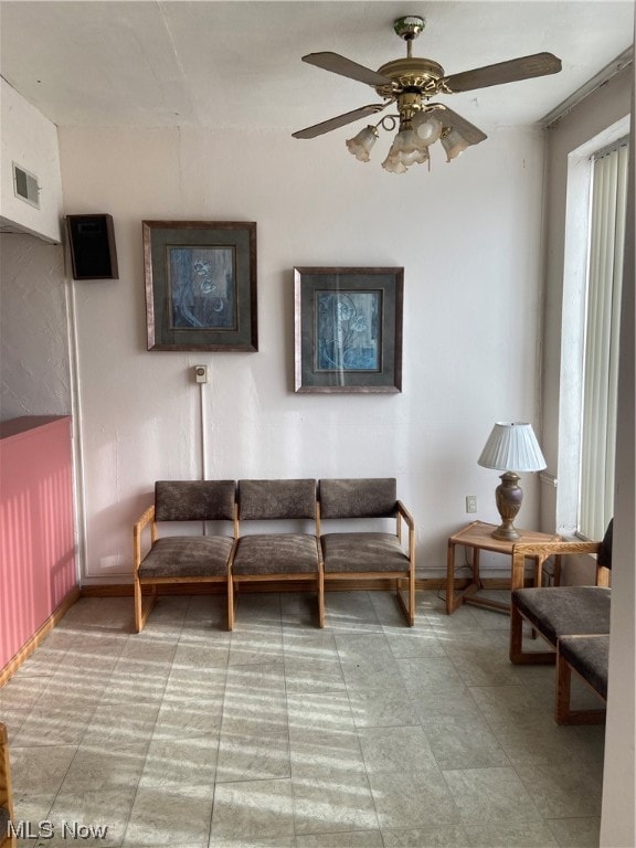 tiled living room featuring ceiling fan and ornamental molding