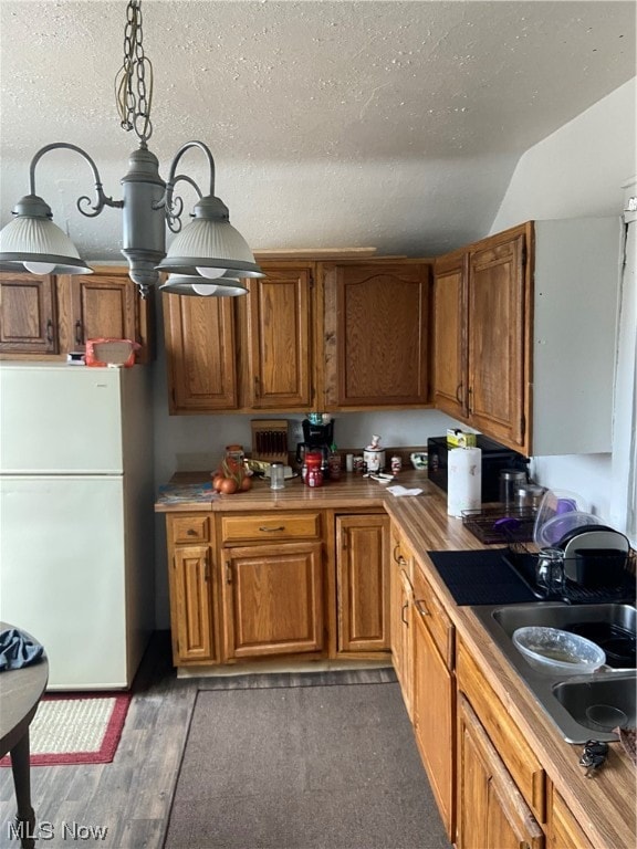 kitchen with sink, a textured ceiling, hardwood / wood-style flooring, and white refrigerator