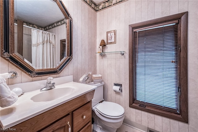 bathroom with oversized vanity, toilet, and wooden walls