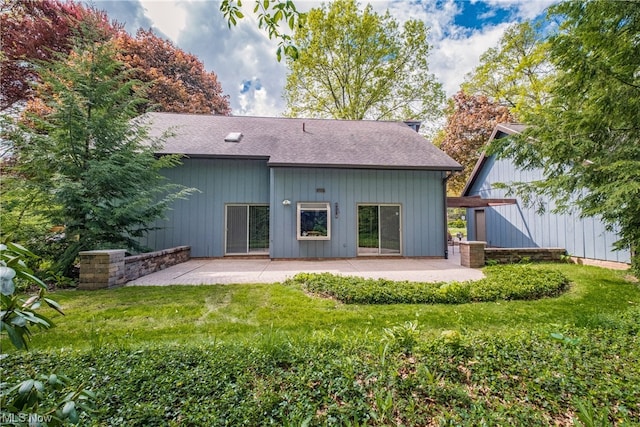 back of property with a lawn and a patio