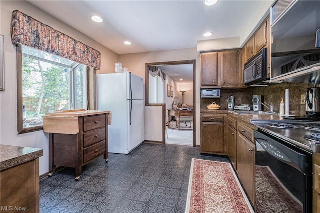 kitchen with dark tile floors, tasteful backsplash, black appliances, and sink