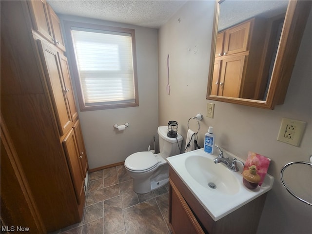 bathroom with vanity, toilet, and a textured ceiling