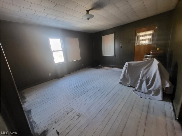 empty room with light hardwood / wood-style flooring and wood walls