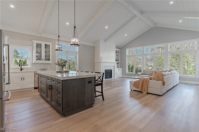 kitchen with a center island, beamed ceiling, light hardwood / wood-style floors, and white cabinets